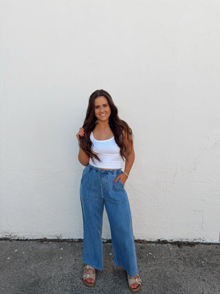 Woman modeling a white tank and blue jeans