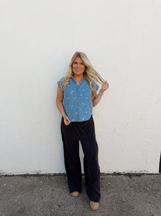Woman modeling a denim floral top and black pants