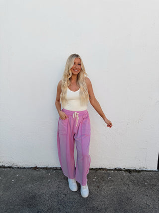 Person in a pink outfit standing on a white wall with a gray floor.