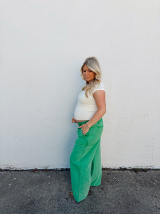 Woman modeling an ivory top and green pants