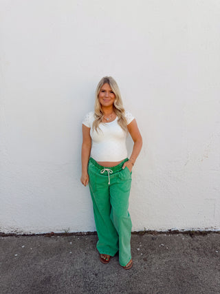 Woman modeling an ivory top and green pants