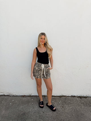 Woman modeling leopard shorts and a black tank