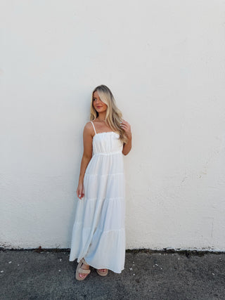 Woman in a white dress standing on a white wall and black asphalt surface