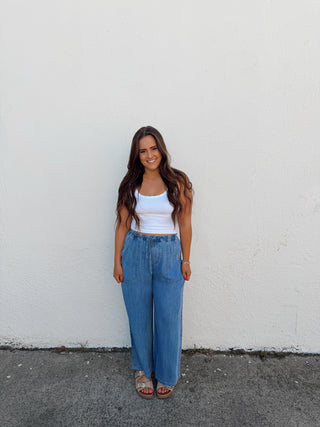 Woman modeling a white tank and blue jeans