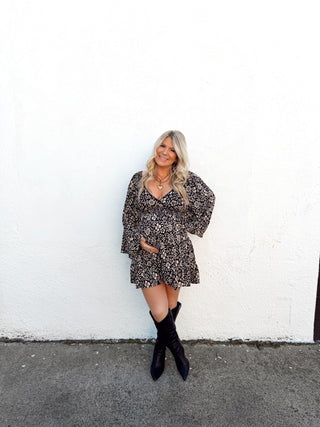 Woman in a floral dress standing on a white and gray pavement.