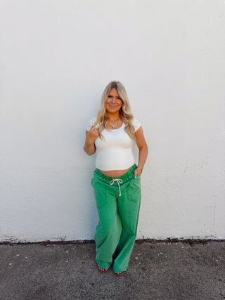 Woman modeling an ivory top and green pants