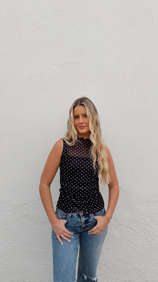 Woman modeling a black polka dot mesh tank