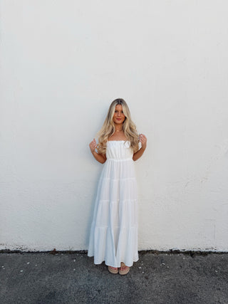 Person wearing a white dress standing on a white surface with a black border