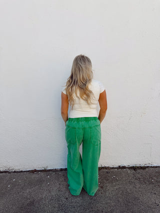Woman modeling an ivory top and green pants