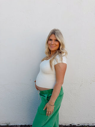 Woman modeling an ivory top and green pants