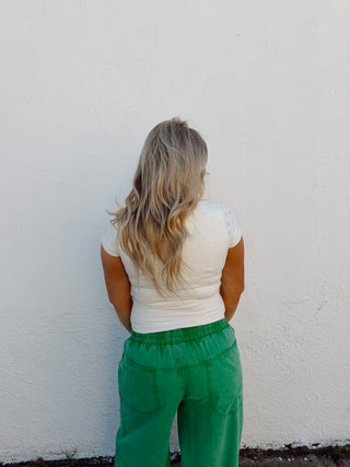 Woman modeling an ivory top and green pants