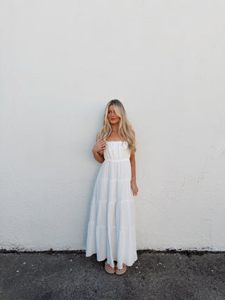 Woman in a white dress standing on a white floor with a black border