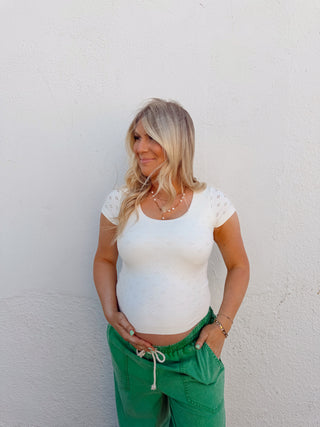Woman modeling an ivory top and green pants