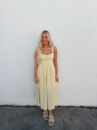 Woman in a yellow dress standing on a white surface with a black border