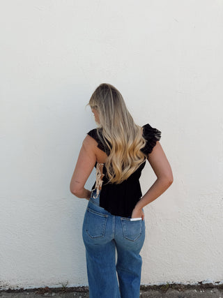 Woman modeling a black top with white detailing and jeans