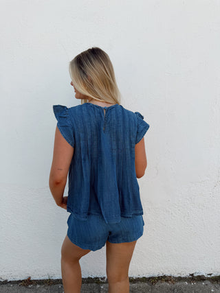 Woman wearing a blue set against a white wall
