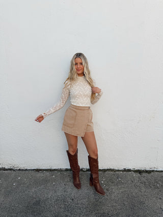 woman wearing a cream lace top and taupe skort